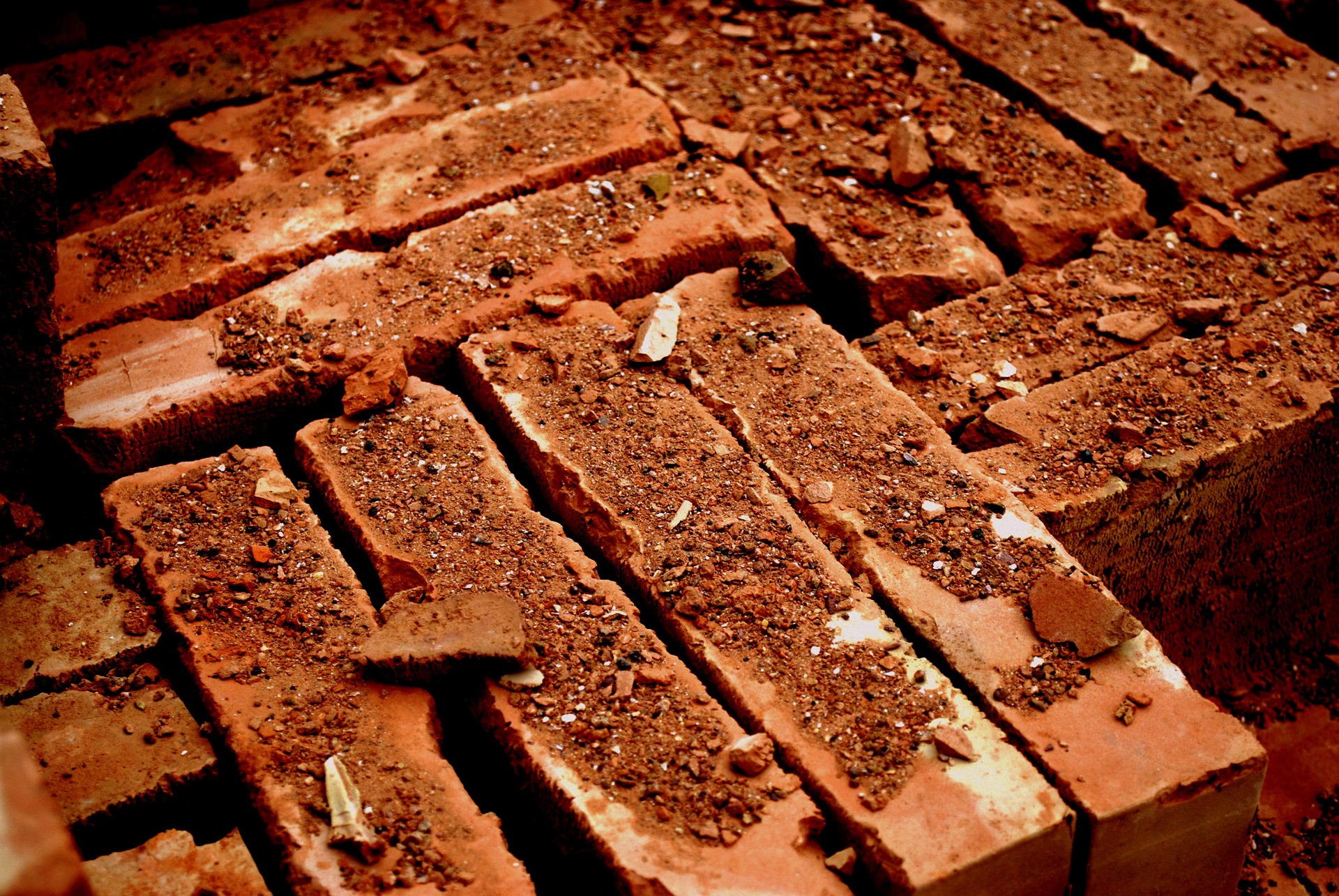 A pile of worn bricks covered in dust and chips of other bricks. 