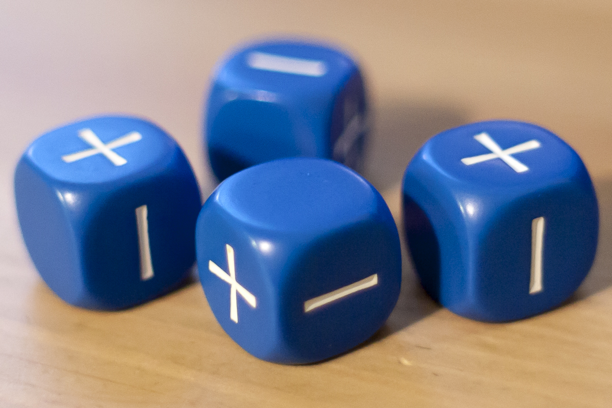 A set of four blue Fate dice resting on top of a wooden table. 