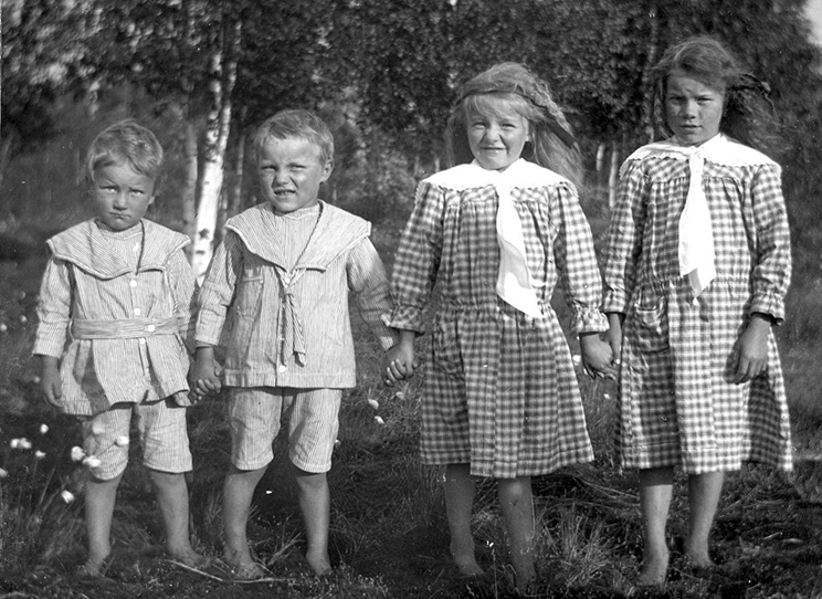A photo of four Swedish children, two boys and two girls, taken sometime in the 1920s. The boys are wearing matching clothes, and the girls are wearing matching dresses.