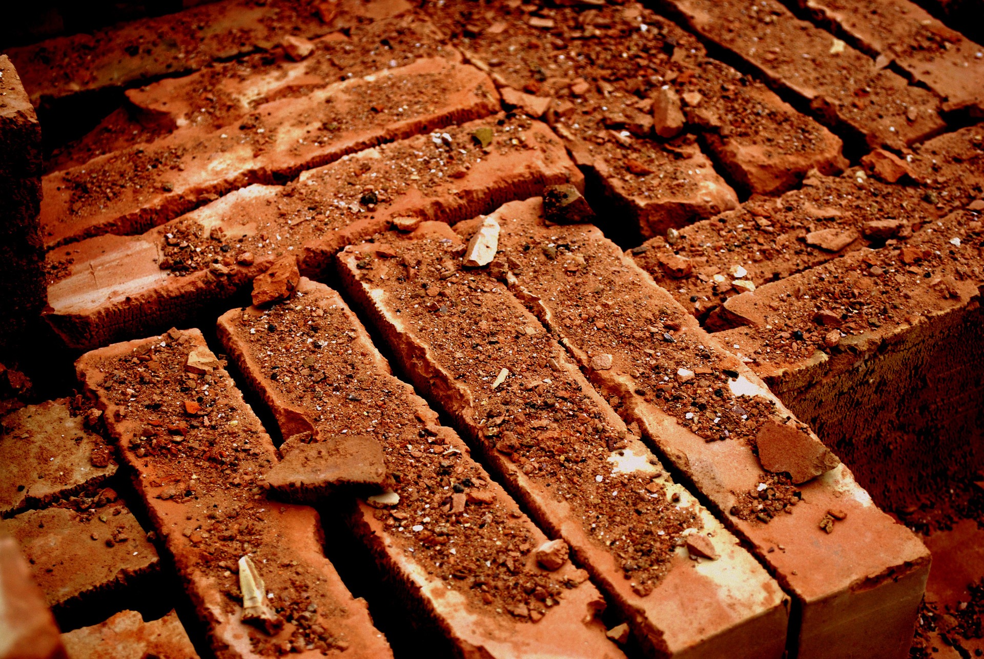 A pile of worn bricks covered in dust and chips of other bricks.