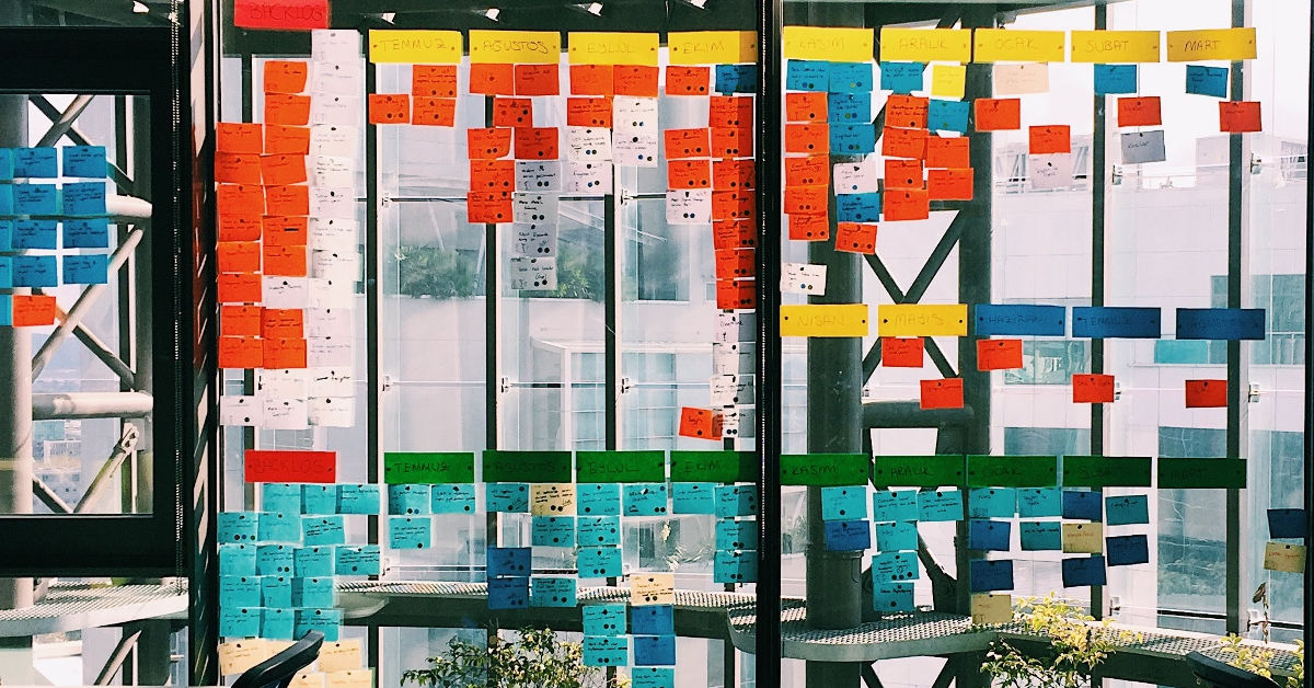 Colorful sticky notes arranged in a grid on the window of an office building. 