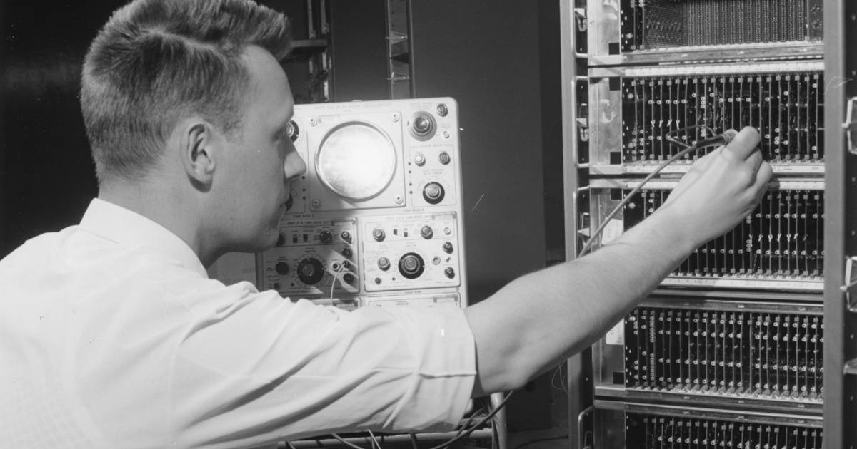 A black and white photo of a man in a short-sleeve collared shirt uses an osciliscope to adjust a circuit board on a Stansaab 'Censor' computer at Standard Radio's factory in Ulvsunda, Stockholm. 