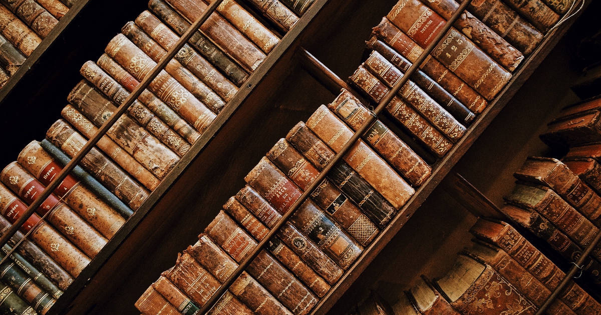 A picture of old books on shelves taken at an angle.